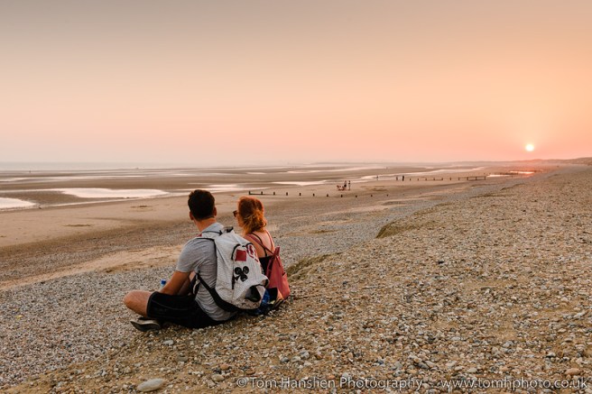 A couple enjoying the sunset on Camber Sands Beach.